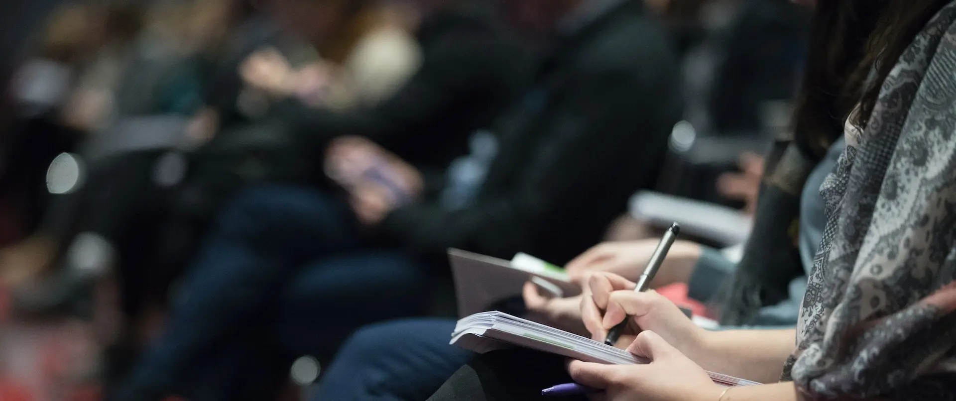 selective focus photography of people sitting on chairs while writing on notebooks